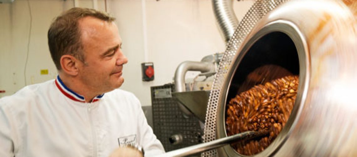 Chef roasting nuts in industrial oven.